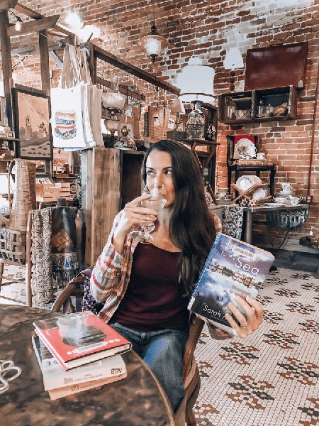 How To Start A Book Review Blog Niche With TUL Holding A Book And Wine