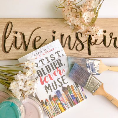 How to start a bookstagram flat lay example one with Artist, Soldier, Lover, Muse, paint jars, paint brushes, and a wooden live inspired sign